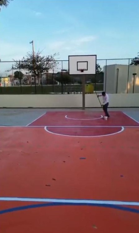 Marcus pintando as linhas de uma quadra poliesportiva vermelha