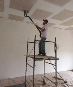 Pintor em andaime pintando forro de salão